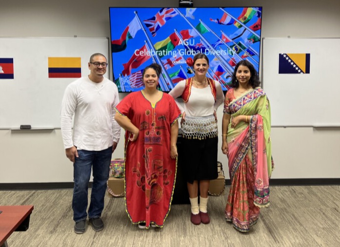 Four people standing next to each other, wearing different cultural outfits to demonstrate diversity at AGNE.